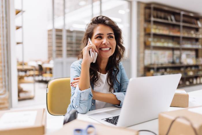 A Small Business Female entrepreneur speaking on the phone while working.